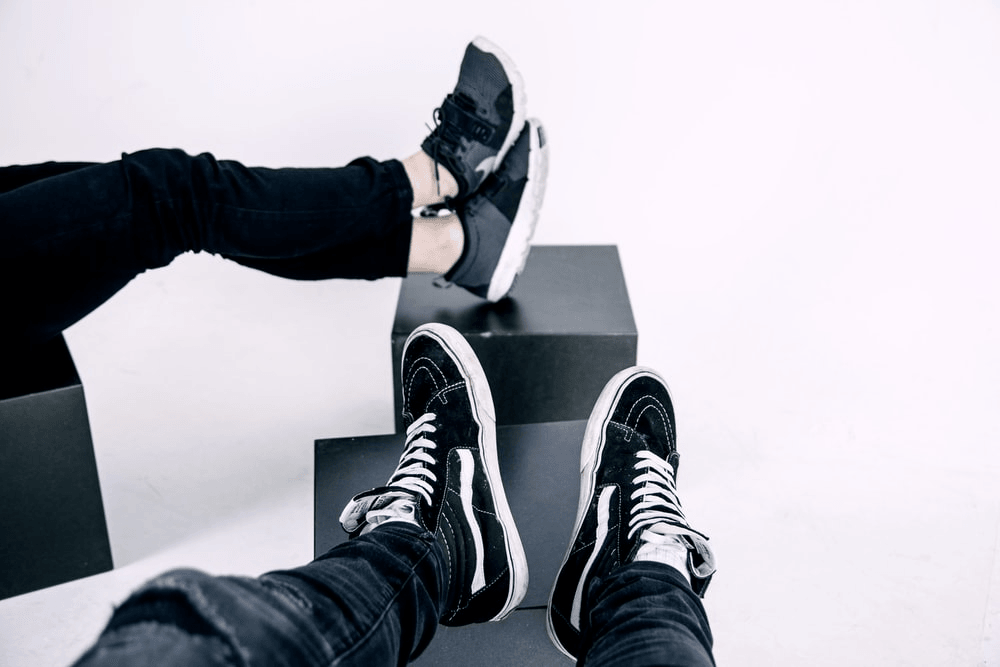A couple wearing black sneakers. 