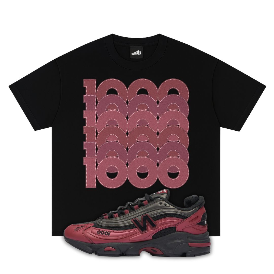 Black t-shirt with red geometric design and a red and black New Balance 1000 Monarch Burgundy sneaker below on a white background