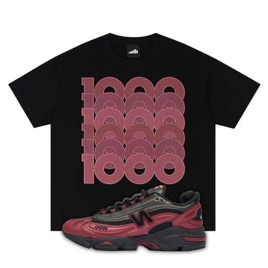 Black t-shirt with red geometric design and a red and black New Balance 1000 Monarch Burgundy sneaker below on a white background