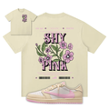 Beige t-shirt with floral design and 'SHY PINK' text, paired with a sneaker on a white background.