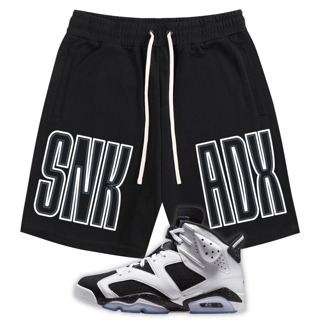 Black athletic shorts with white drawstrings and large white outlined 'SNK ADX' text on the sides, shown with a black, white, and gray Jordan 6 Oreo sneaker on a plain white background.