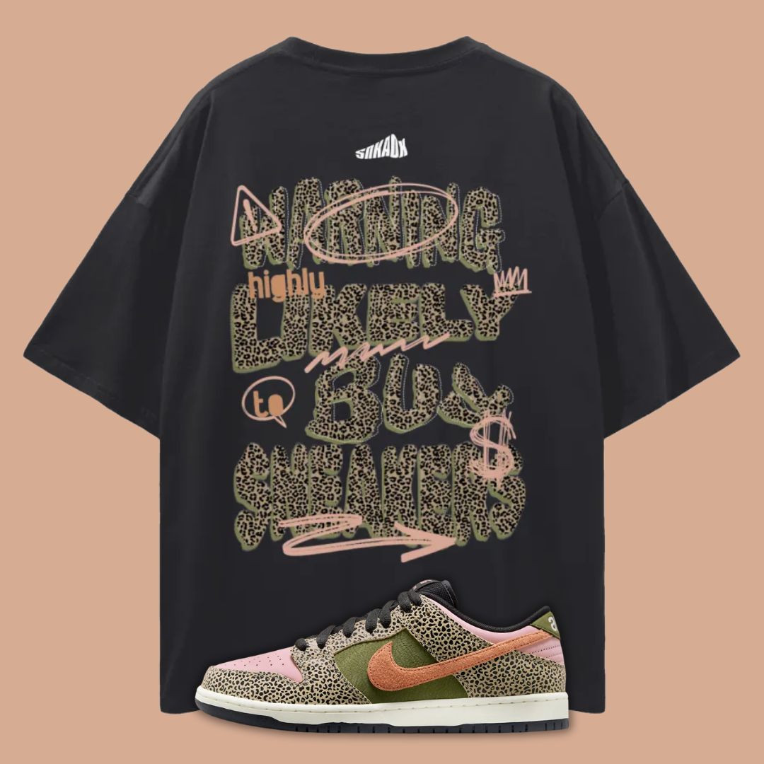 Black t-shirt with colorful text design on a beige background, paired with a sneaker.
