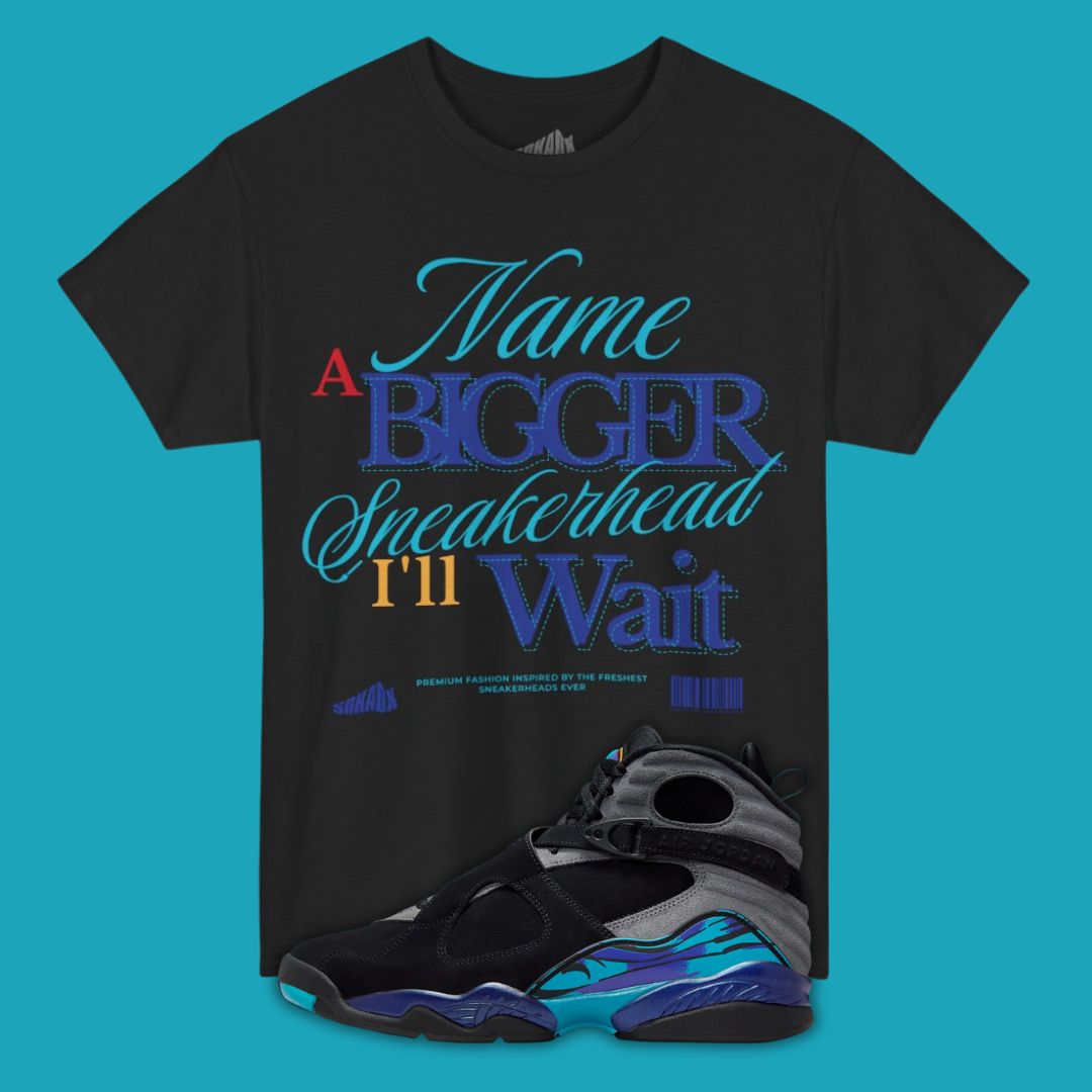 Black typography t-shirt with colorful text Name a Bigger Sneakerhead I'll Wait and a pair of sneakers on a blue background