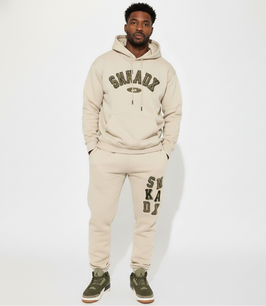Man wearing a beige 'SNKADX' hoodie and pants on a white background
