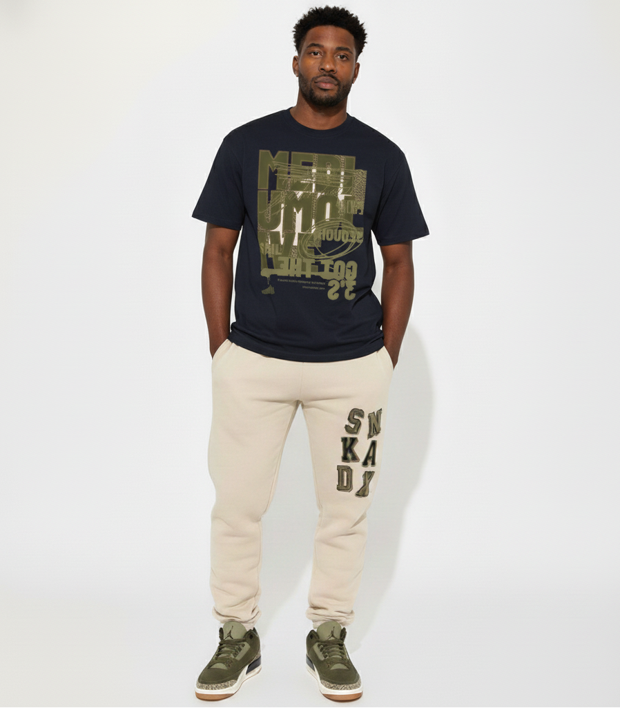 Man wearing a black t-shirt with graphic design and beige sweatpants with text, standing against a white background.