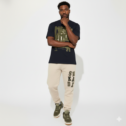 Man wearing a black t-shirt with green text, beige sweatpants with text, and green Air Jordan 3 Family Affair Medium Olive on a white background