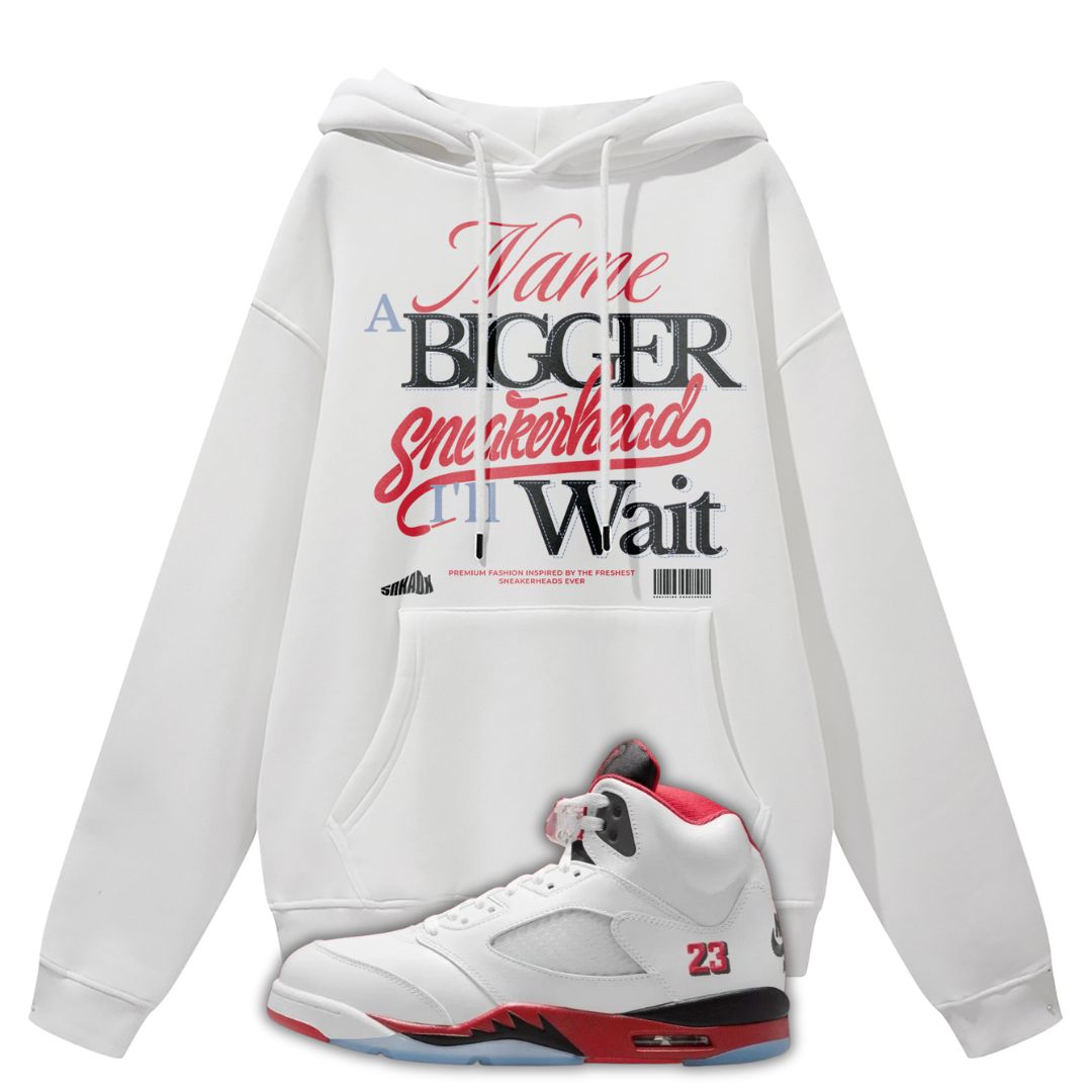 White hoodie with text saying Name A Bigger Sneakerhead I'll Wait and a white sneaker with red and black accents on a white background