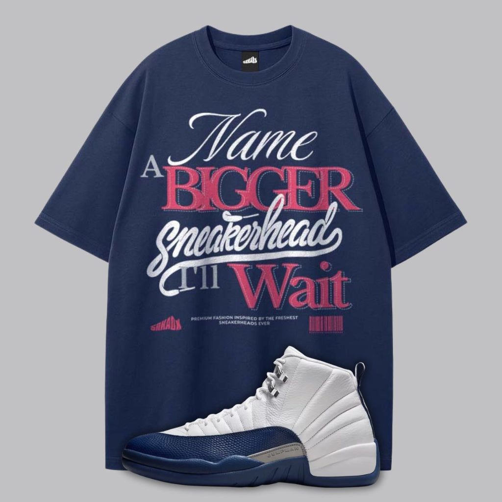 Navy blue t-shirt with typography design and a Air Jordan 12 French Blue on a gray background