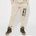 Person wearing a beige 'SNKADX tracksuit on a white background