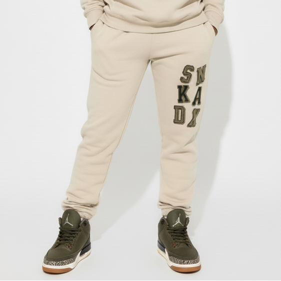 Person wearing a beige 'SNKADX tracksuit on a white background