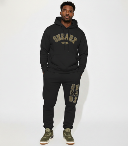 Person wearing a black hoodie and jogger set with 'SNKADX' branding on a white background