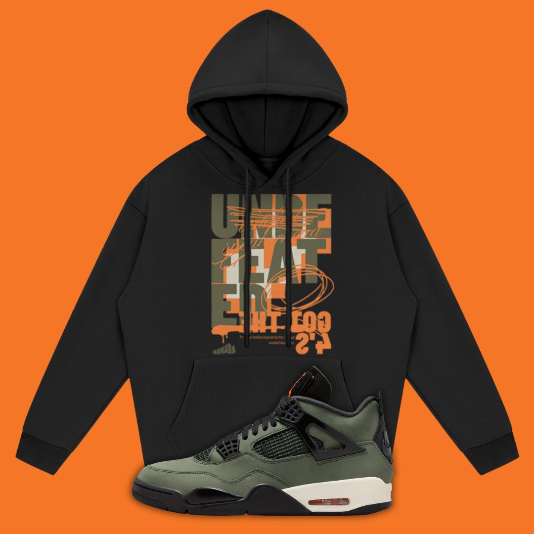 Black hoodie with graphic design and a Air Jordan 4 Undefeated sneaker on an orange background