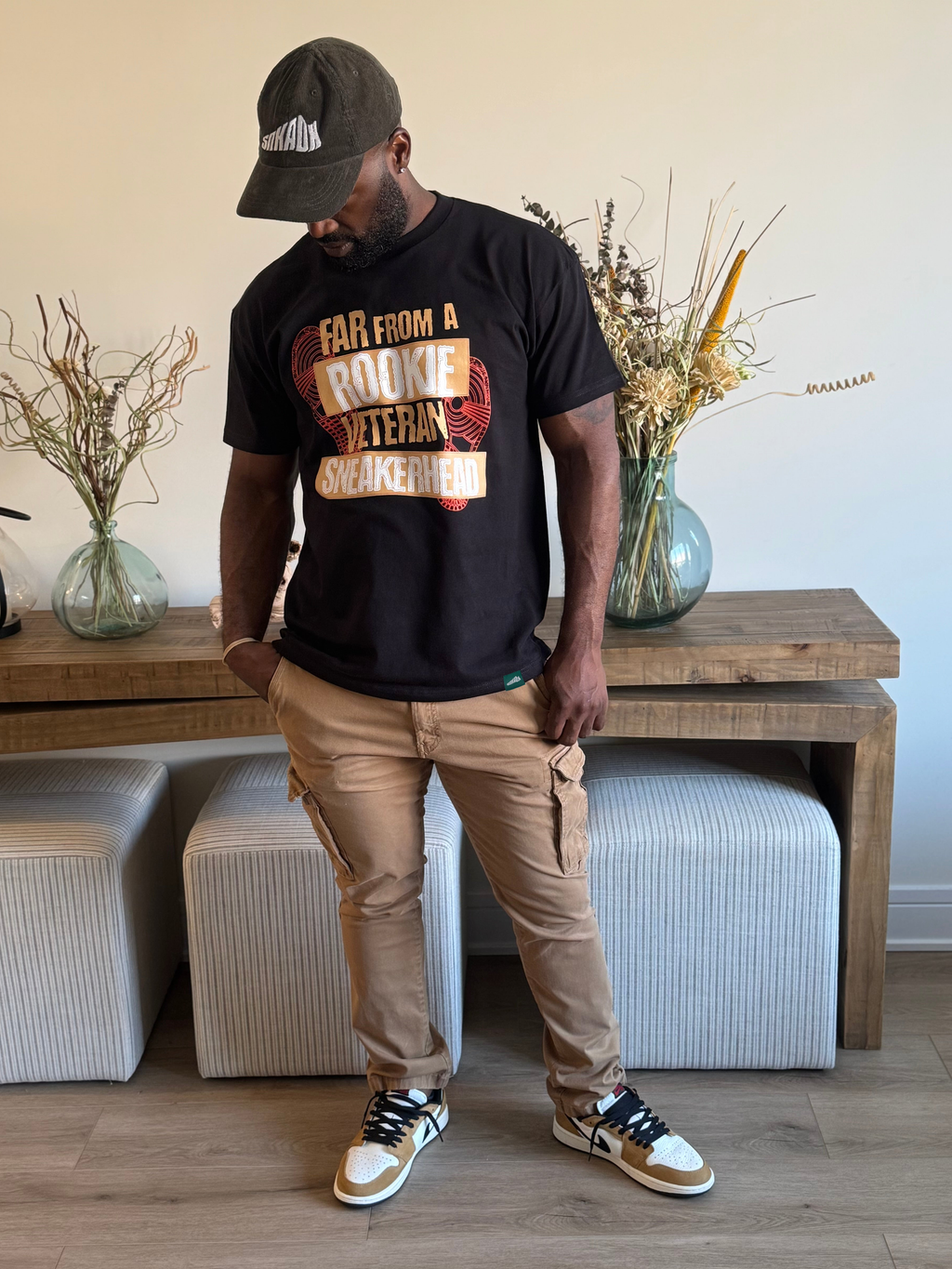 man standing wearing black tee with veteran sneakerhead on the front designed to match air jordan 1 rookie of the year